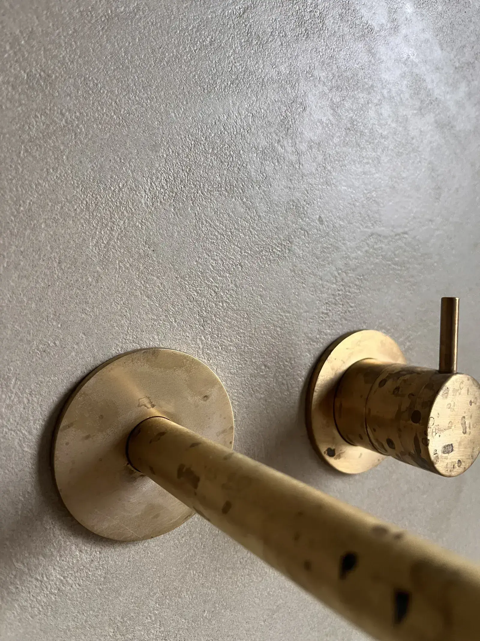 Detail van messing kraanwerk tegen Quartz Coarse microcement textuur