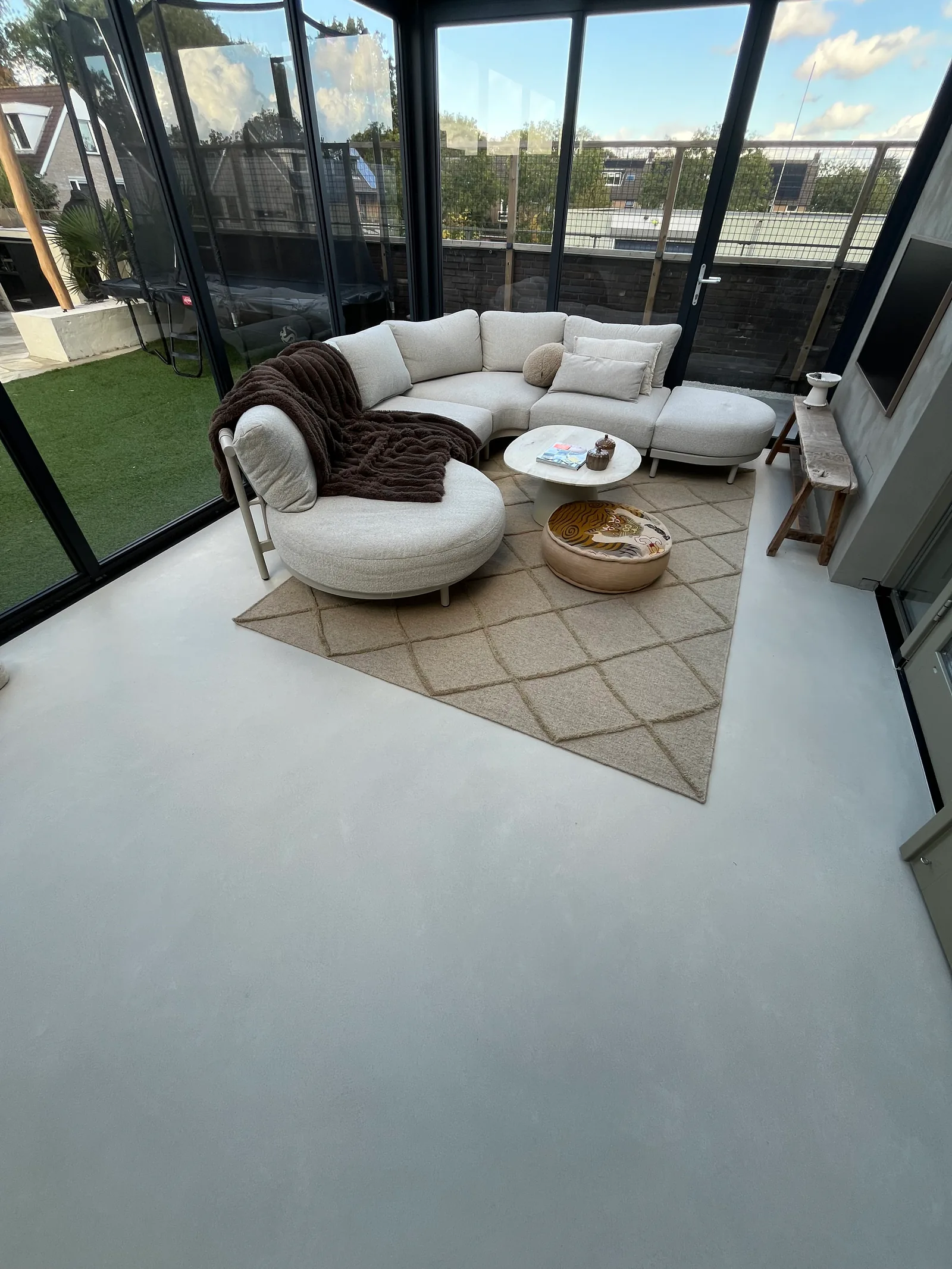 Woerden sunroom with Honey 2 microcement flooring, a light seating area and glazed walls