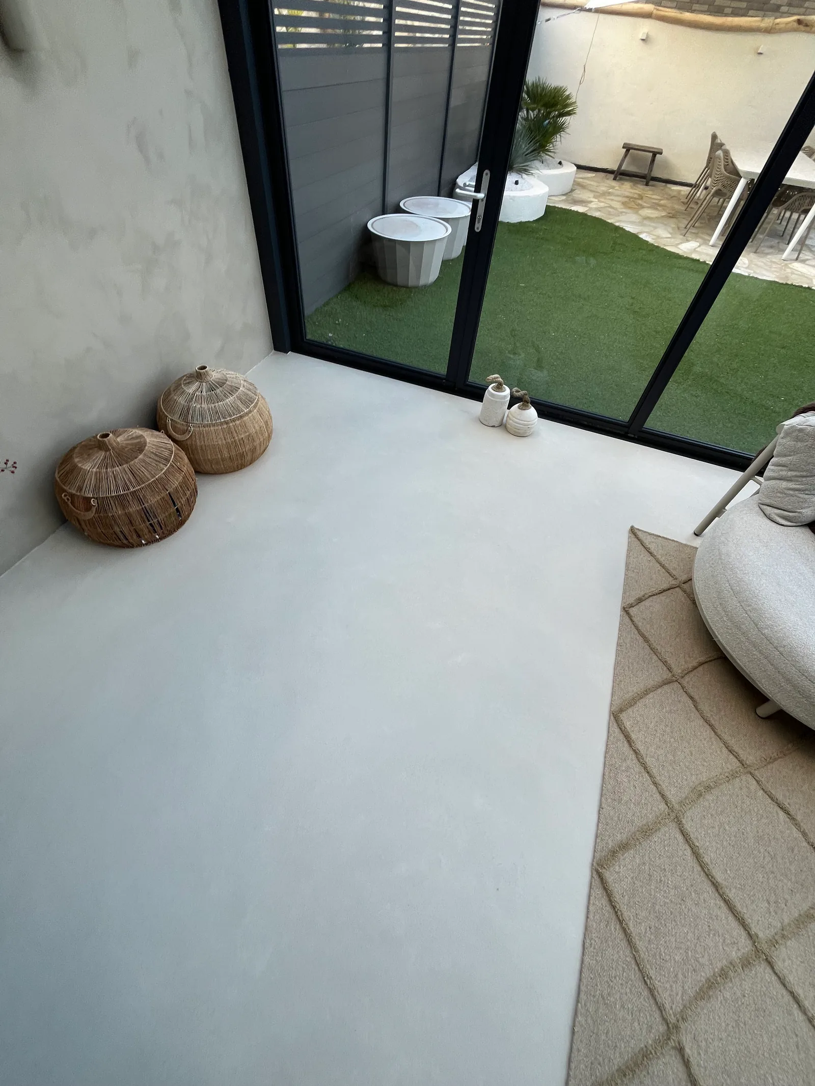 Microcement floor along the black-framed glazing overlooking the garden in Woerden