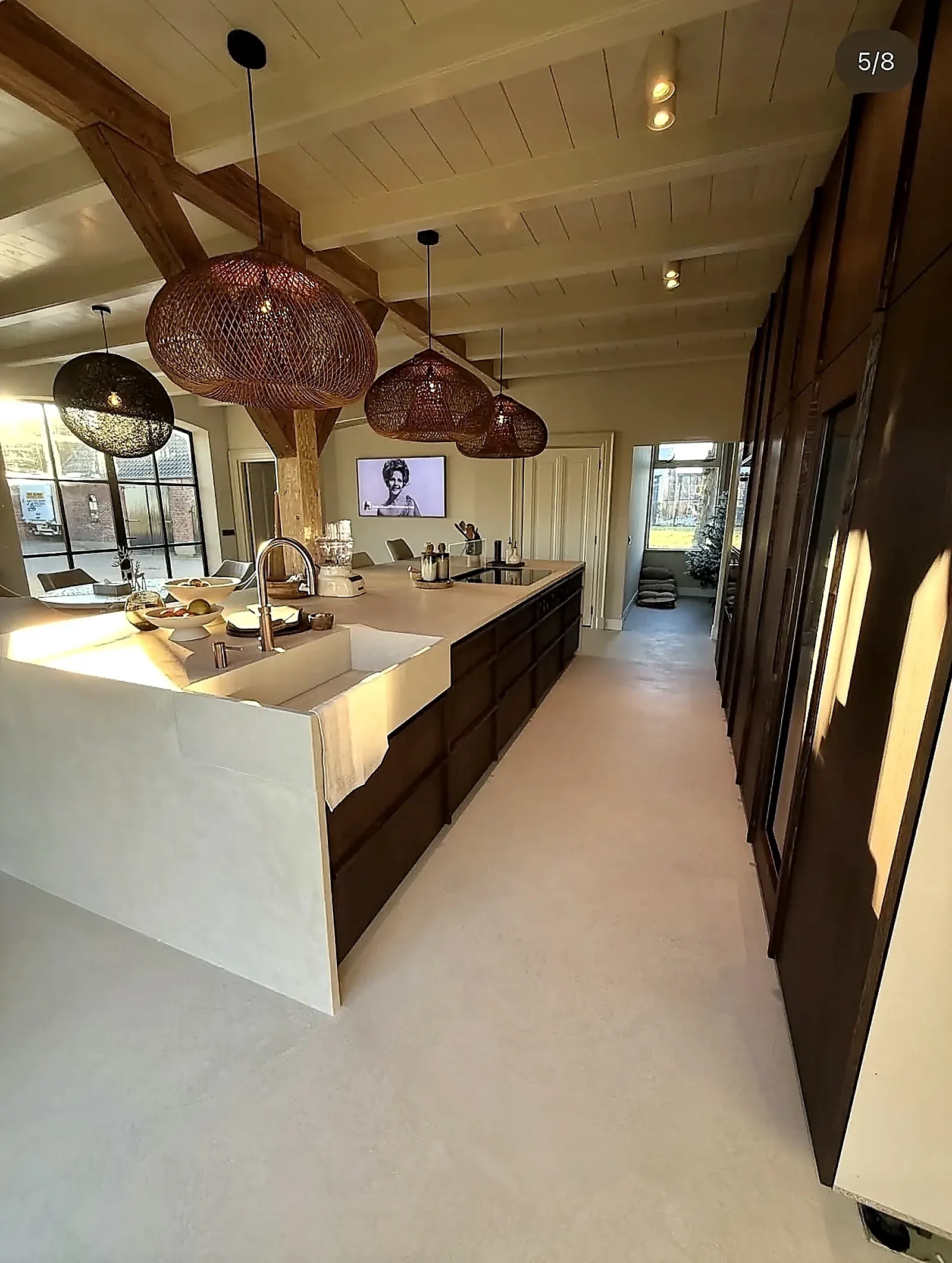 Microcement kitchen island with sink and sunlight through steel-framed windows in farmhouse Harmelen