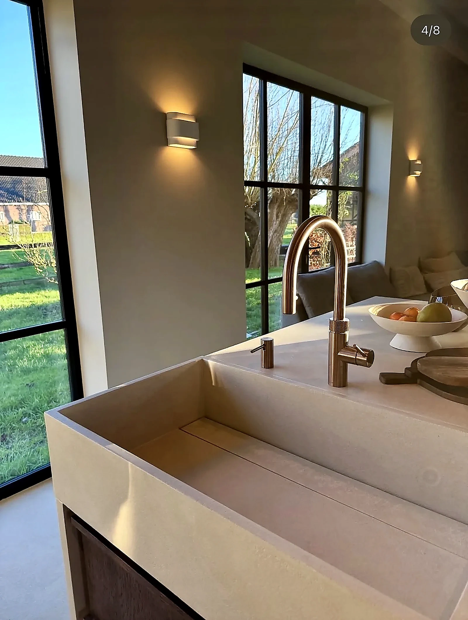 Detail of microcement sink with copper tap and garden view in farmhouse