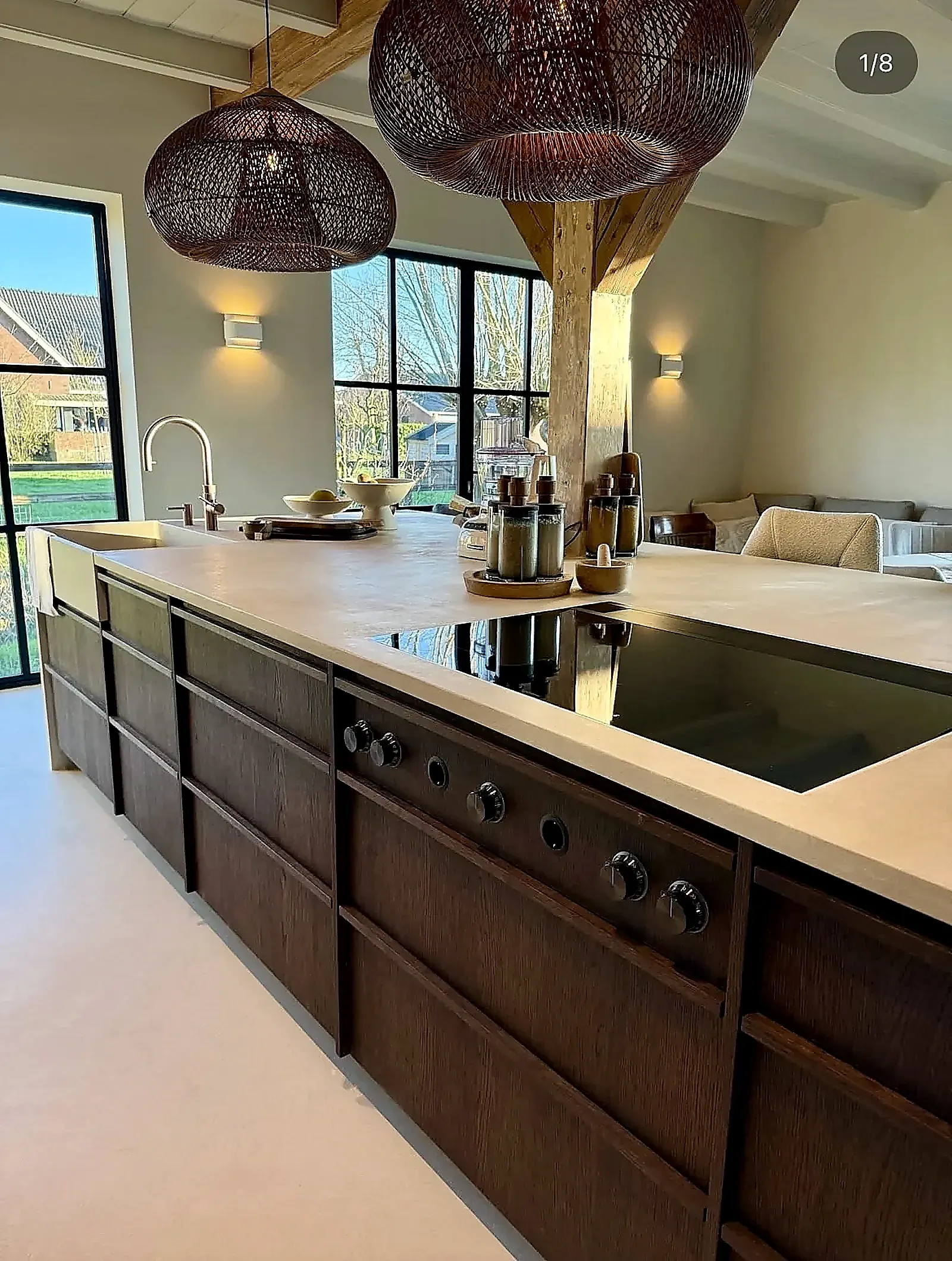 Microcement countertop with cooktop, wooden beams and rattan lamps in farmhouse Harmelen